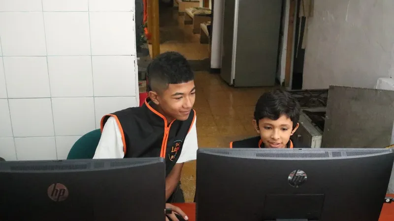 Dos niños trabajando juntos frente a un computador
