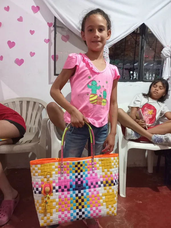 Una niña sostiene un bolso tejido hecho en los talleres