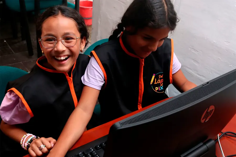 Dos niñas riendo frente a un computador durante un taller