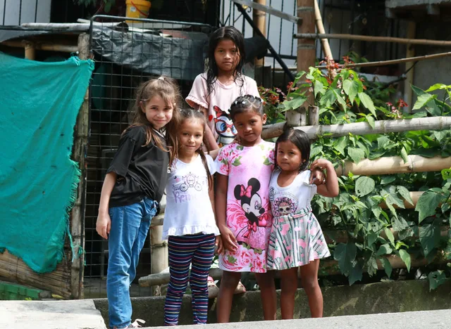 Niñas del barrio posando frente a una huerta
